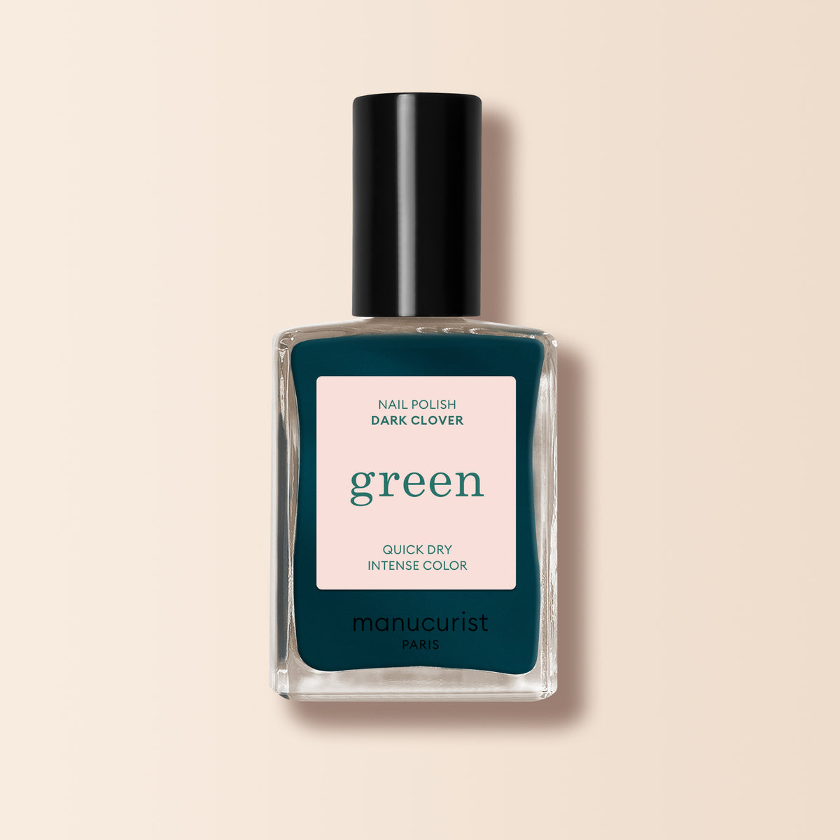 A bottle of Manucurist Dark Clover nail polish with a black cap and dark green shade sits against a light beige background. The label reads: Nail Polish Dark Clover, green, Quick Dry Intense Color, manucurist Paris.