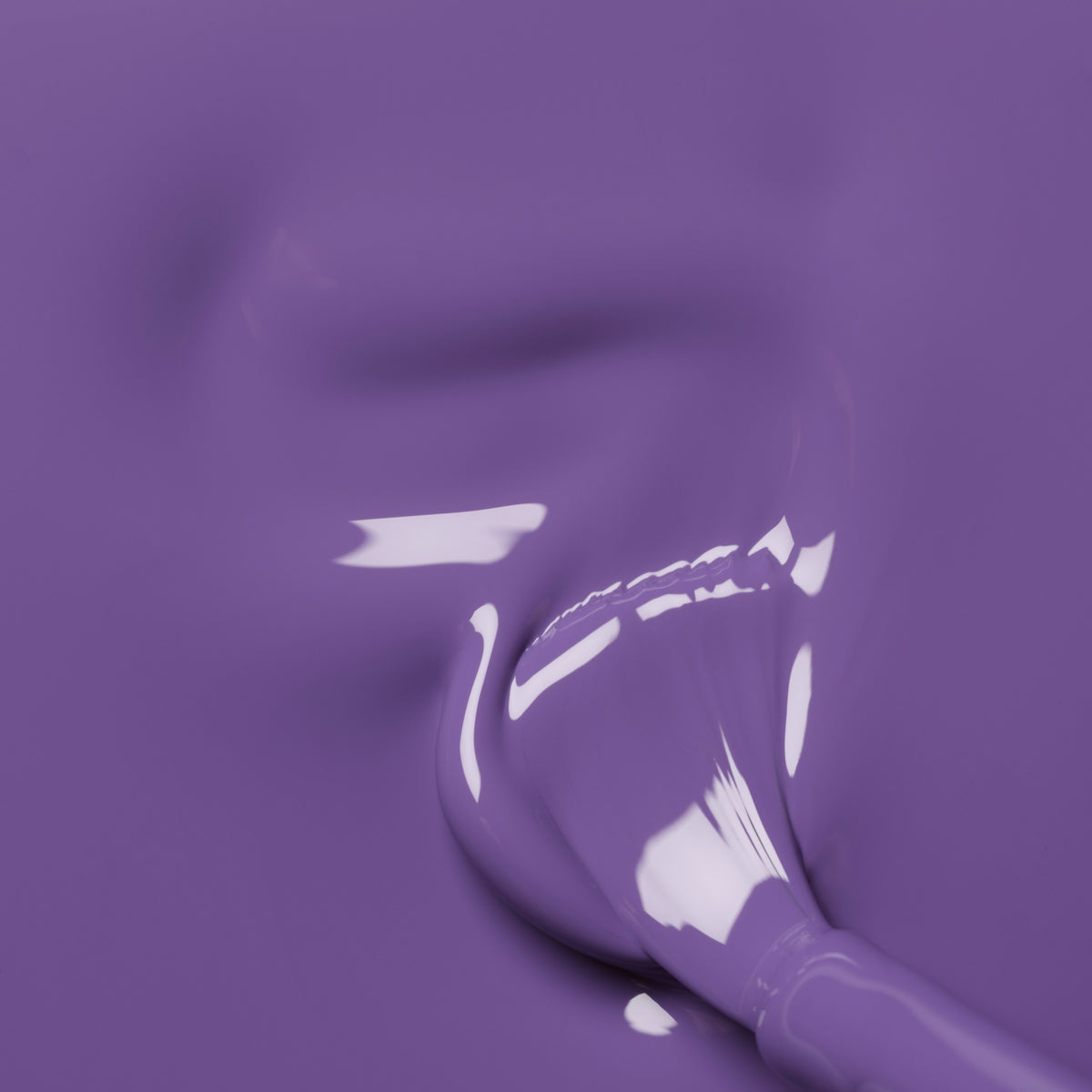 A close-up of a paintbrush coated in Manucurist’s Iris, a glossy purple gel polish, blending into a smooth, shiny surface with subtle blue undertones and visible reflections.