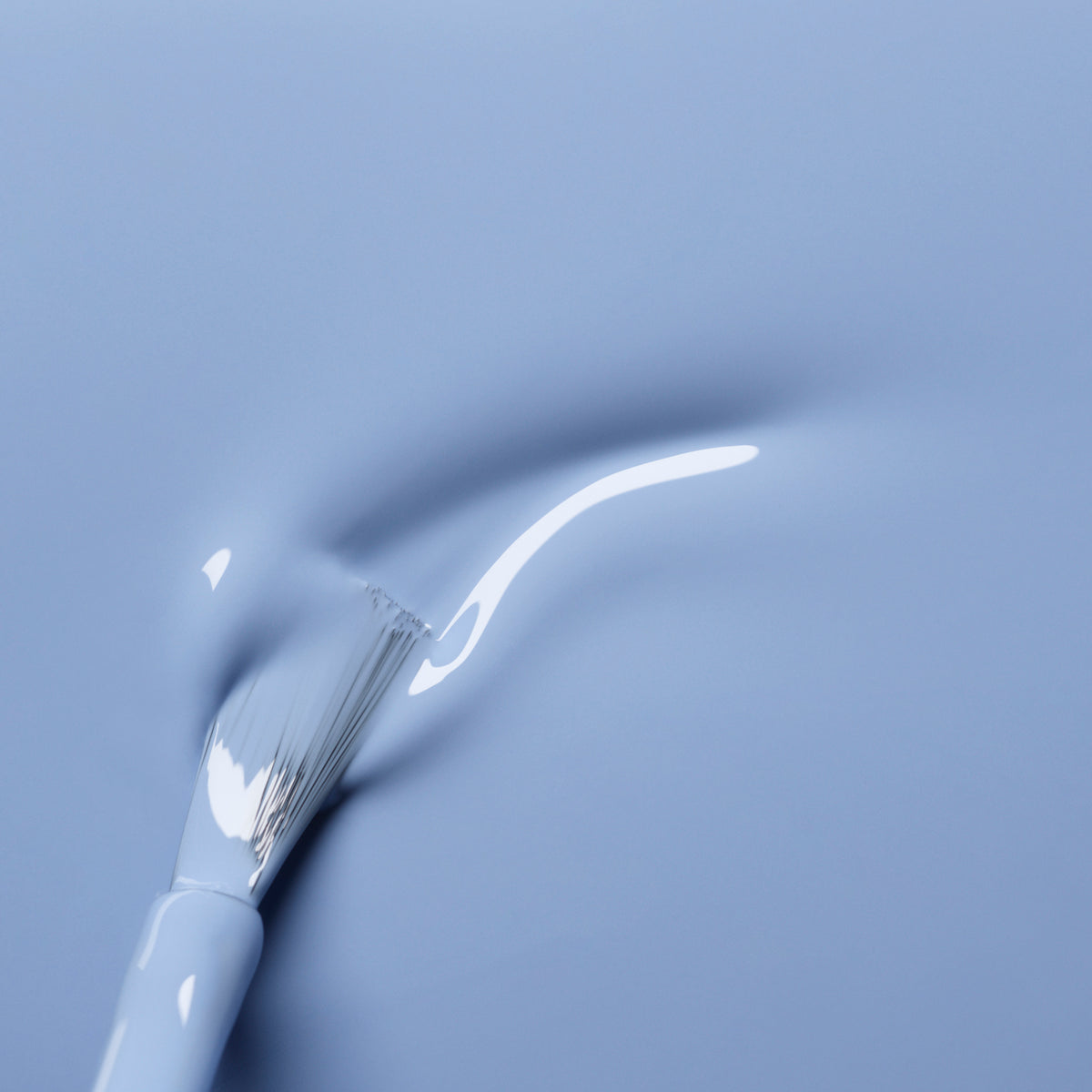A close-up of the Manucurist Lilas white brush applying pastel blue nail polish, creating a smooth, glossy streak on a matching blue surface.