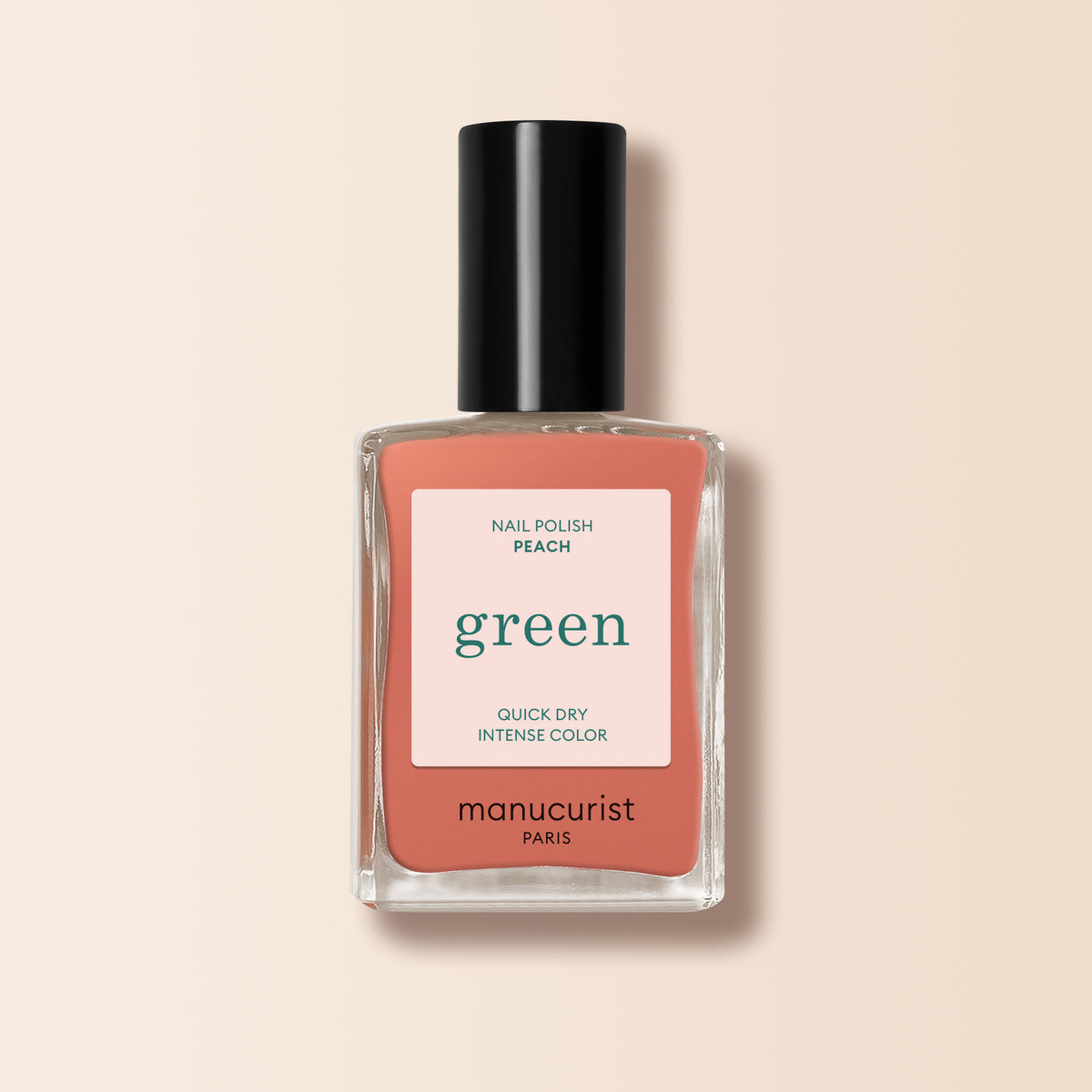 A bottle of Manucurist nail polish in the shade Peach, with a black cap and peach label featuring white and green text, set on a light beige background. Ideal for adding a subtle summer tint to your nails.
