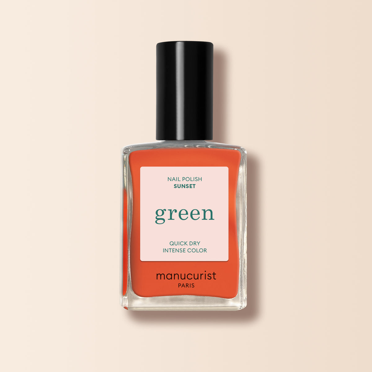 A bottle of Manucurist Sunset nail polish from the Green™ collection, in vibrant orange, with a black cap and white-coral label, displayed on a beige background.