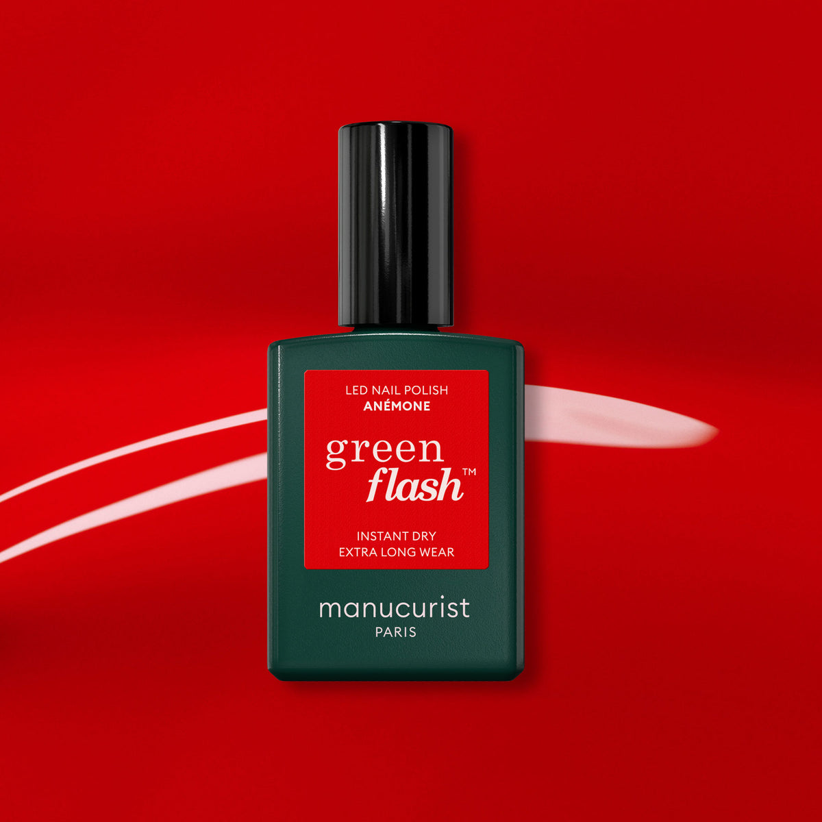 Un flacon de vernis gel Manucurist Anémone se détache sur un fond rouge vif orné d&