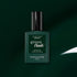 A bottle of Manucurist’s Green Flash LED gel nail polish in the shade Emerald sits centered on a dark green background. The label features the phrases “Instant Dry” and “Extra Long Wear,” emphasizing the gemstone-inspired polish’s rich, sophisticated appearance.