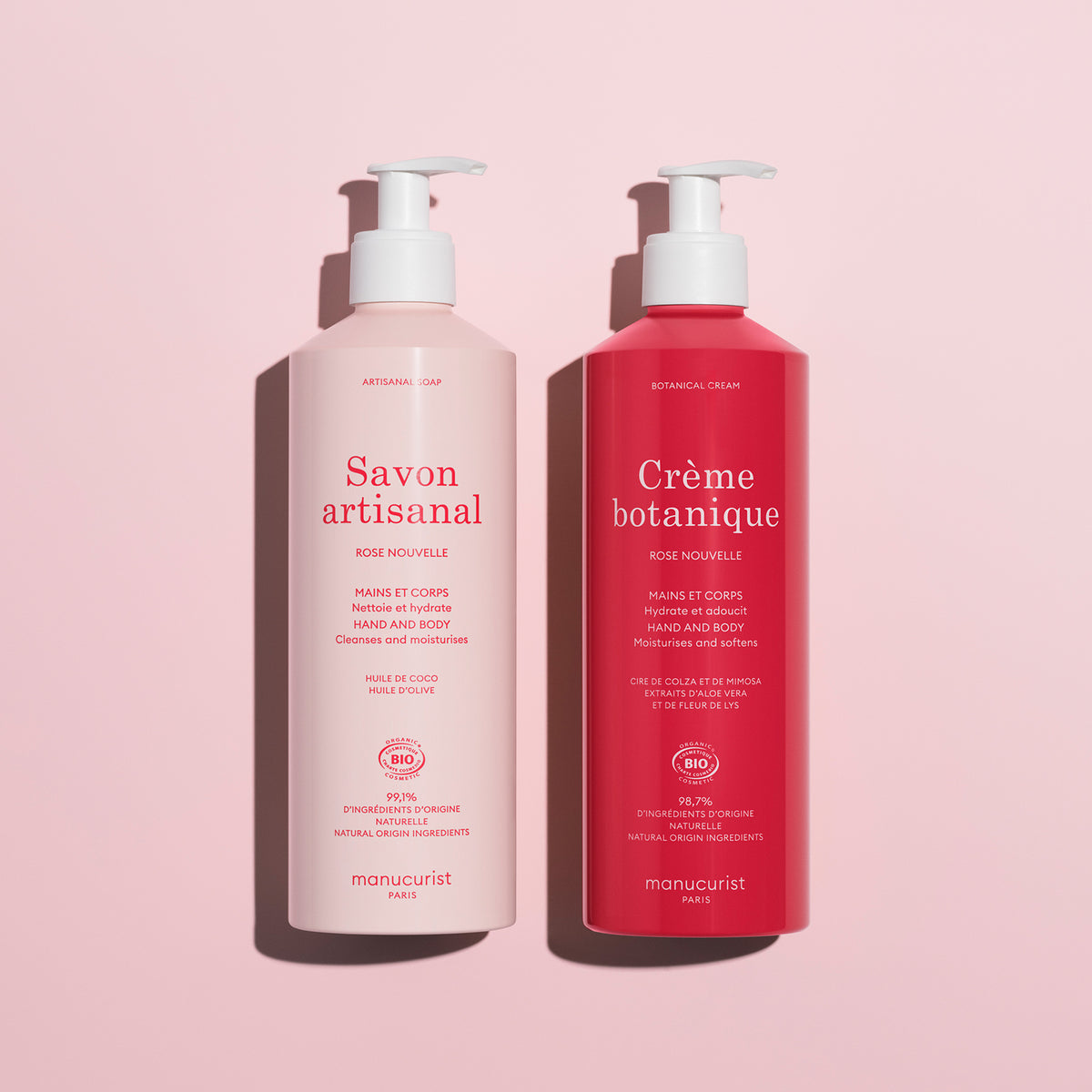 Le duo de savons artisanaux The Rose Botanical Cream - Cosmos Organic by Manucurist comprend deux flacons-pompes roses pour le soin des mains et du corps, délicatement parfumés à la rose, présentés sur un fond rose clair.