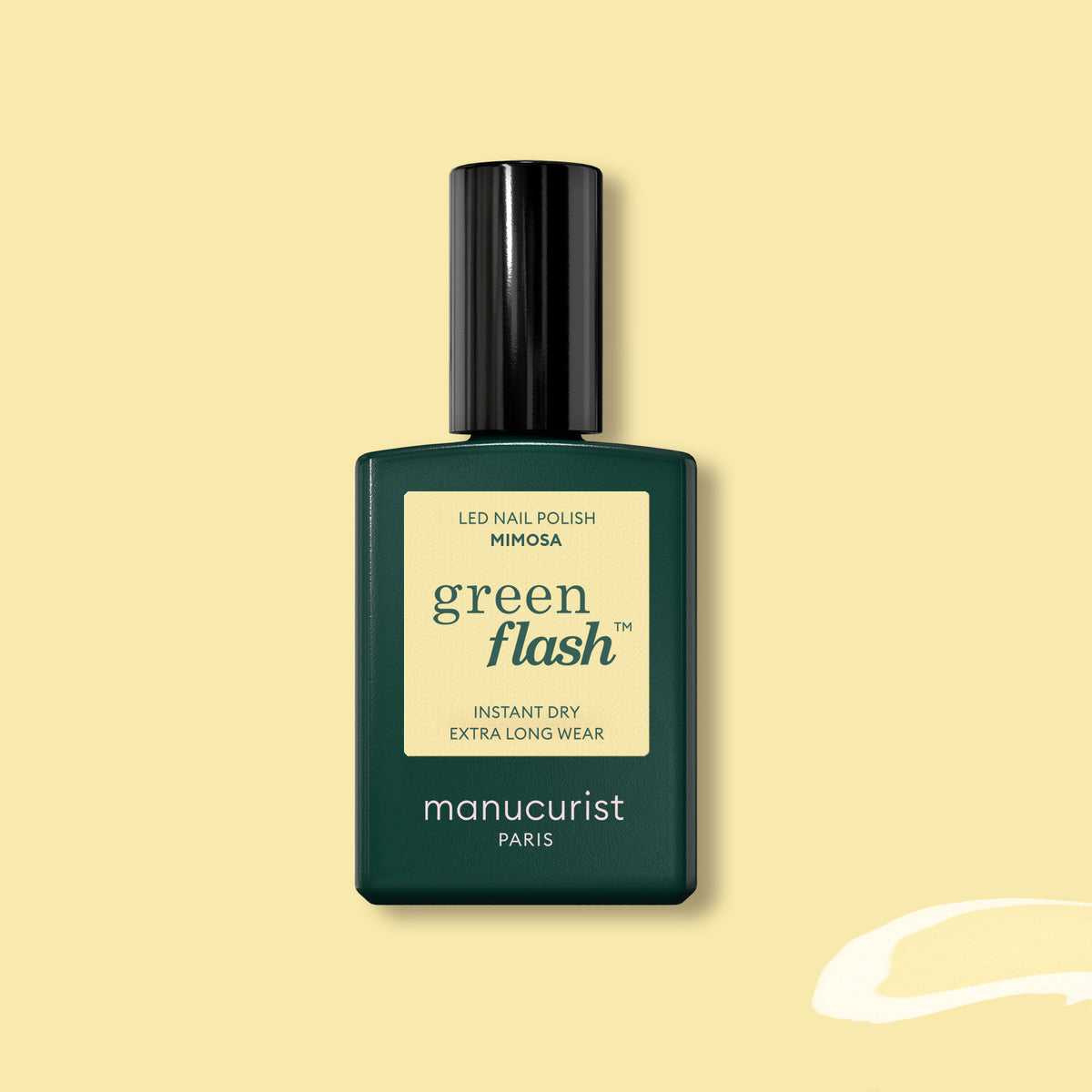 Un flacon de vernis gel Manucurist Mimosa Green Flash, dans un flacon rectangulaire vert foncé avec un bouchon noir et une étiquette jaune pastel, présenté sur un fond jaune clair.