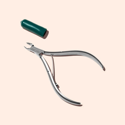 Manucurist Cuticle Clippers—professional stainless steel tool with a curved handle and separate red cap, shown on a light beige background—for neat, precise trimming.